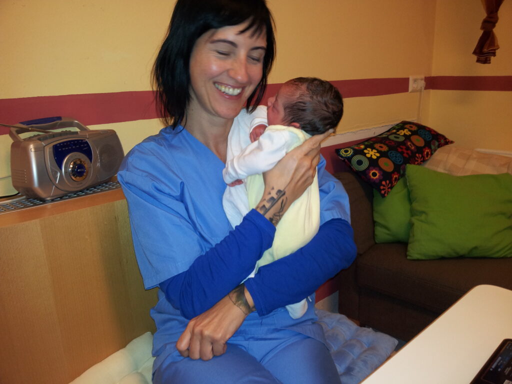 Heidi Winkler in scrubs holding a newborn on the maternity ward
